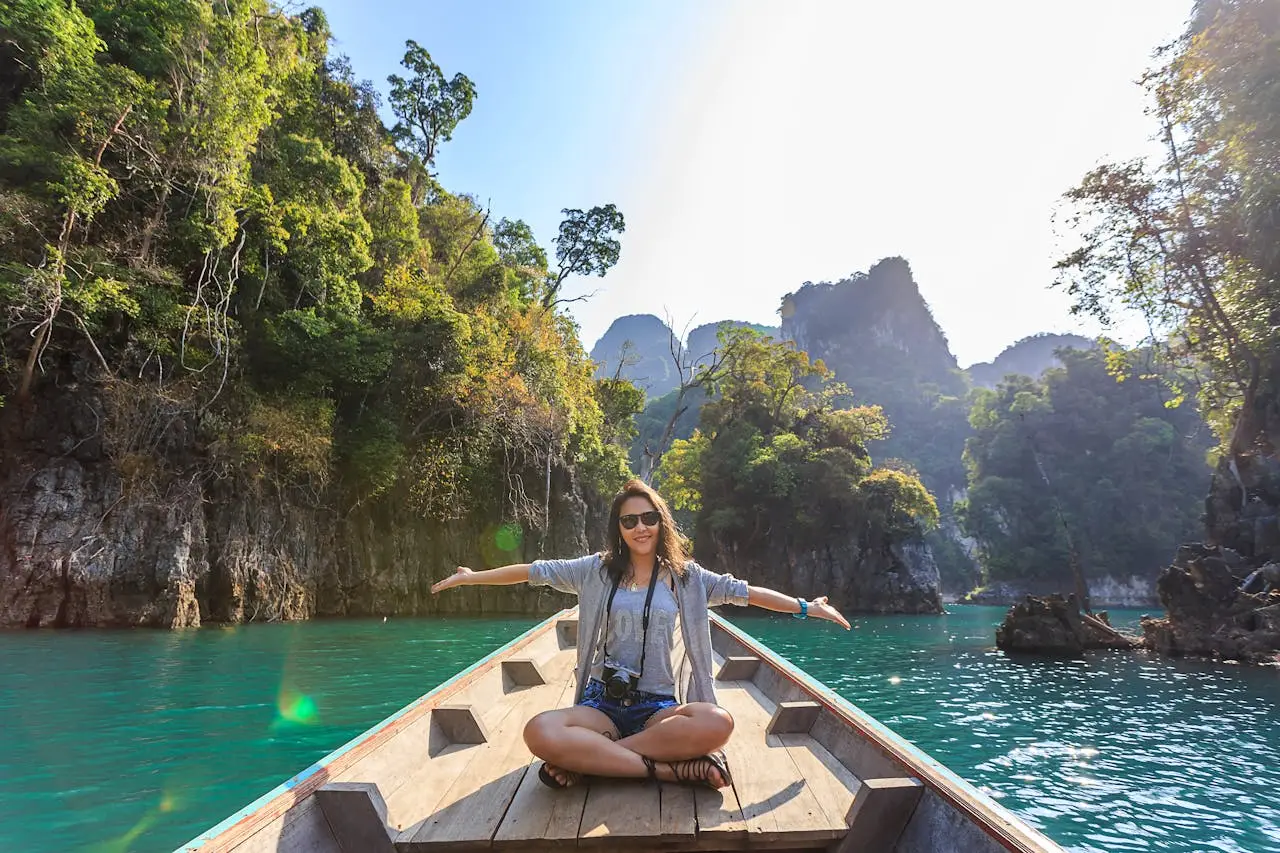 about-us Asian woman relishing a serene boat journey through the lush karst landscape of Thailand's Khlong Sok.